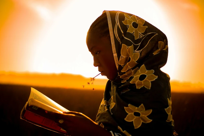 a woman wearing a scarf looking at an open book