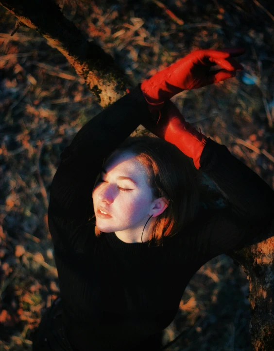 a woman standing by a tree with her hand in the air