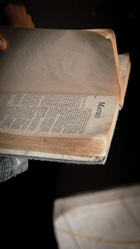 a person is holding an open book and a trash can