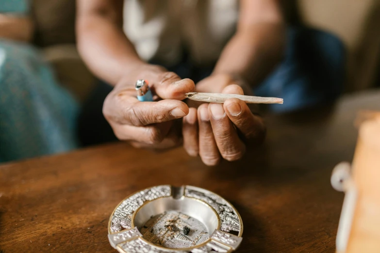 a person holding a cigarette, and other items that are on a table