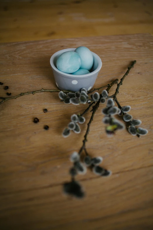 small, hand painted eggs in a bowl on a wood table