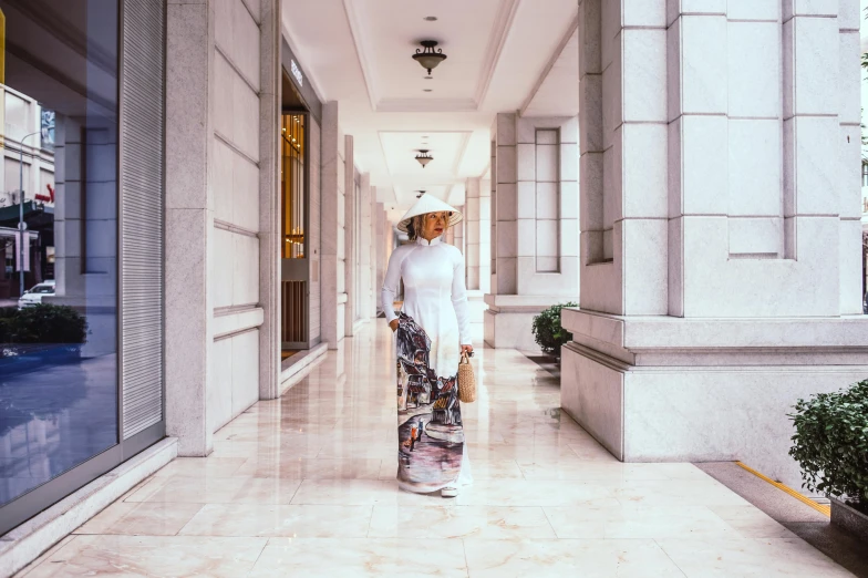 a woman walking down the hallway in a white dress