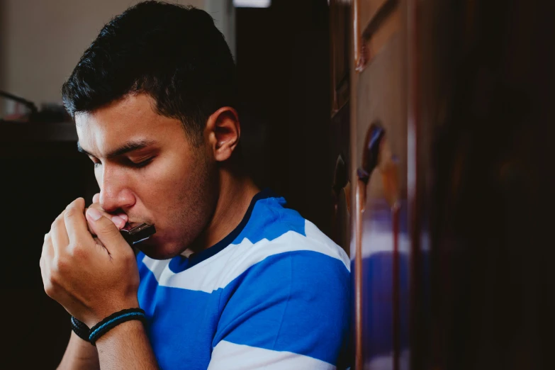 a man is brushing his teeth while leaning against a cabinet