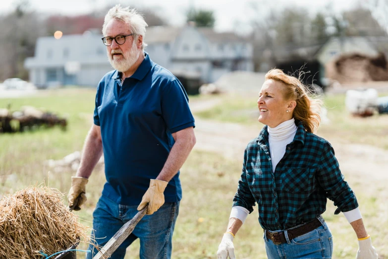 a man and a woman standing in the grass with a wheelbarrow