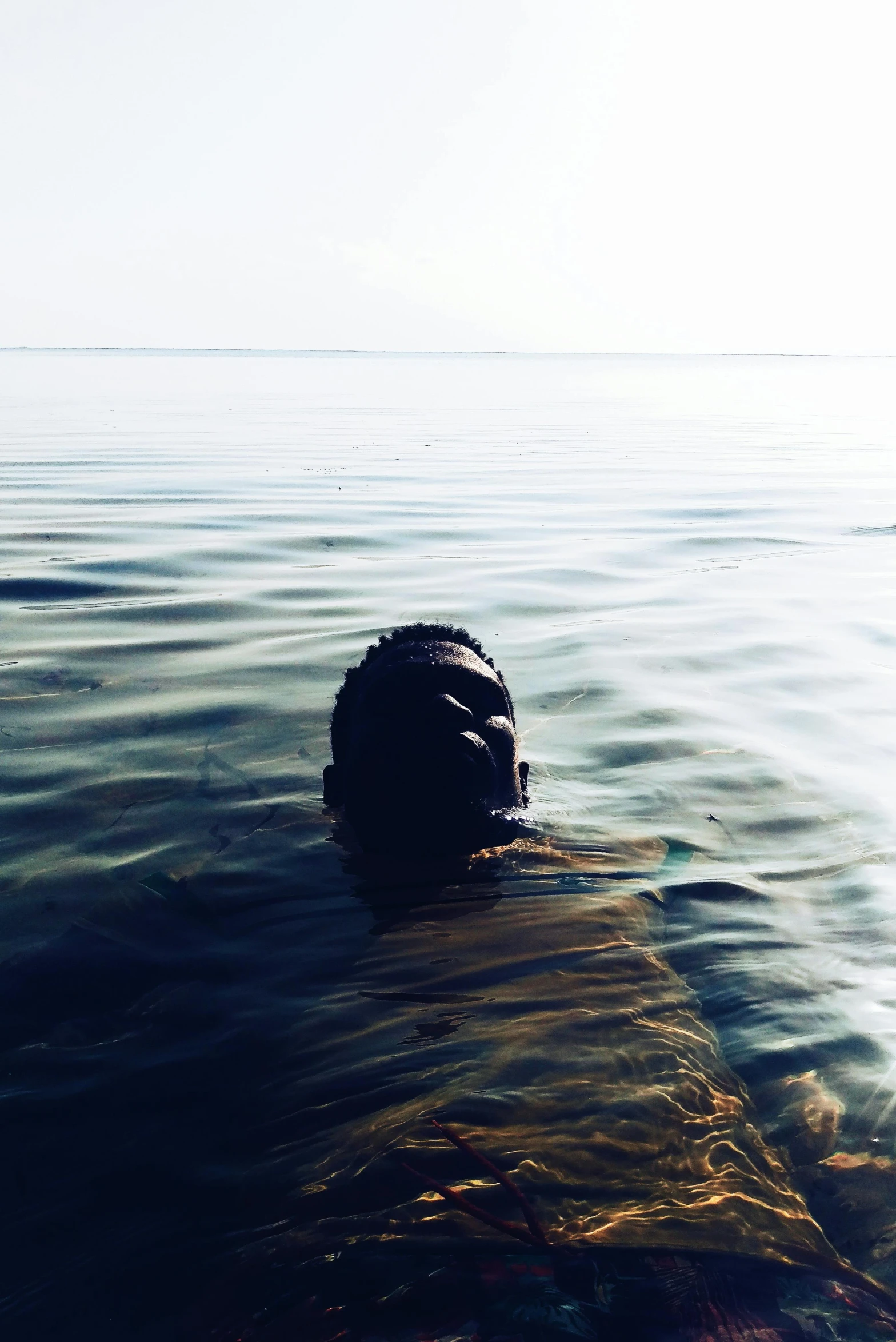 a woman floating in the ocean next to the beach