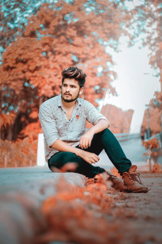 the man is sitting on the ground by some leaves