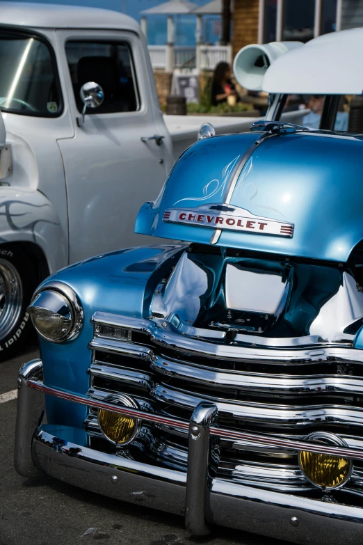 old style blue chevy truck parked next to other older model trucks