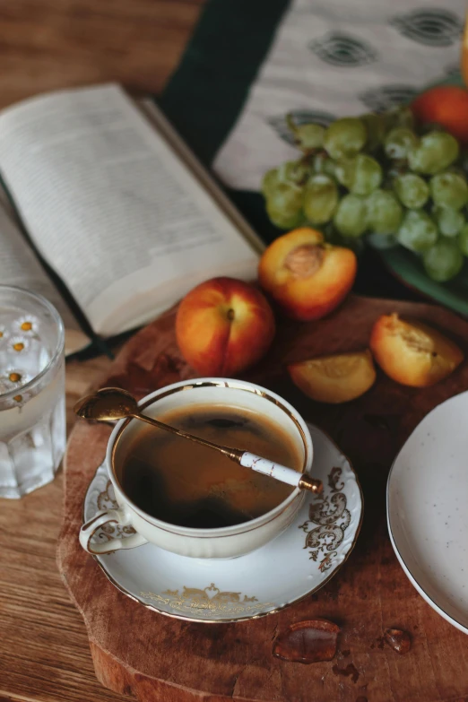 a white plate with an open book on it next to a cup of coffee and bowl with gs