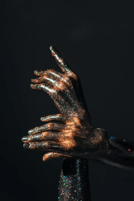 hands reaching out towards the sky with glitter on them