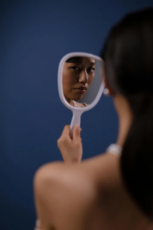 young man looking into mirror while standing in front of blue wall