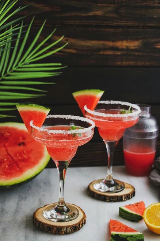 two drinks sitting on top of a table next to sliced watermelon