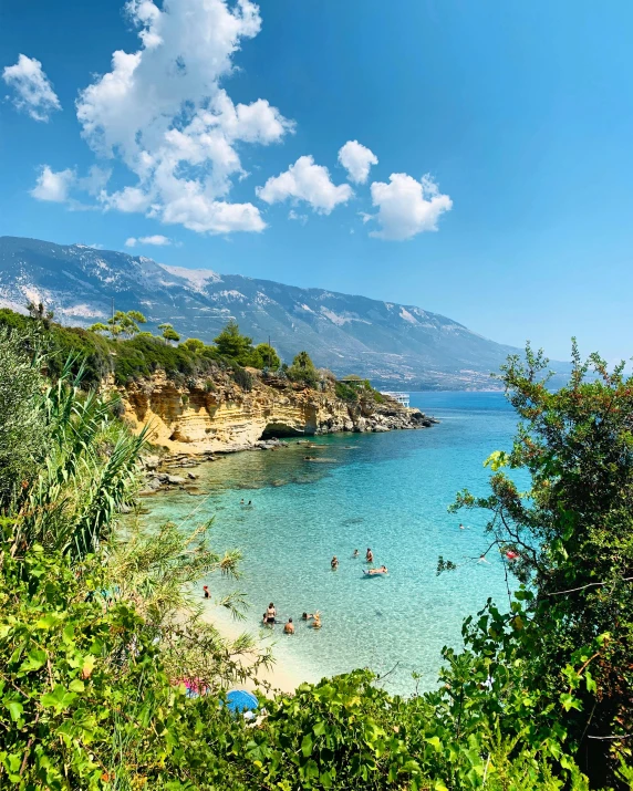 several people swimming in clear blue water on a sunny day