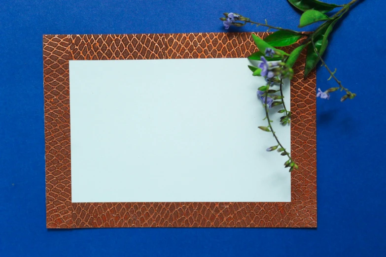 a paper is placed on a blue surface with a flower nearby