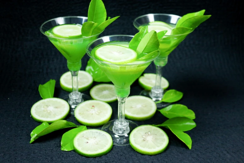 a green drink with ice and lemons on the side