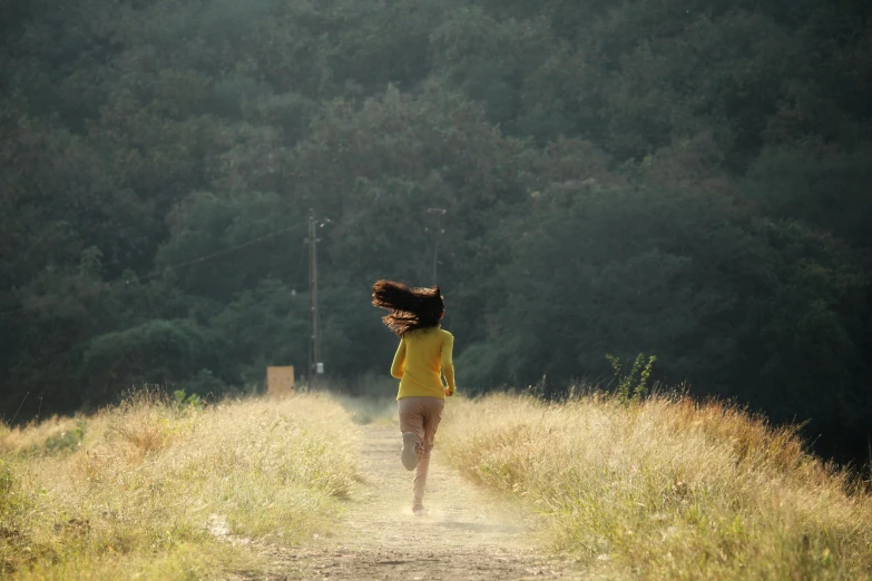 a girl running down a path, she is carrying a frisbee