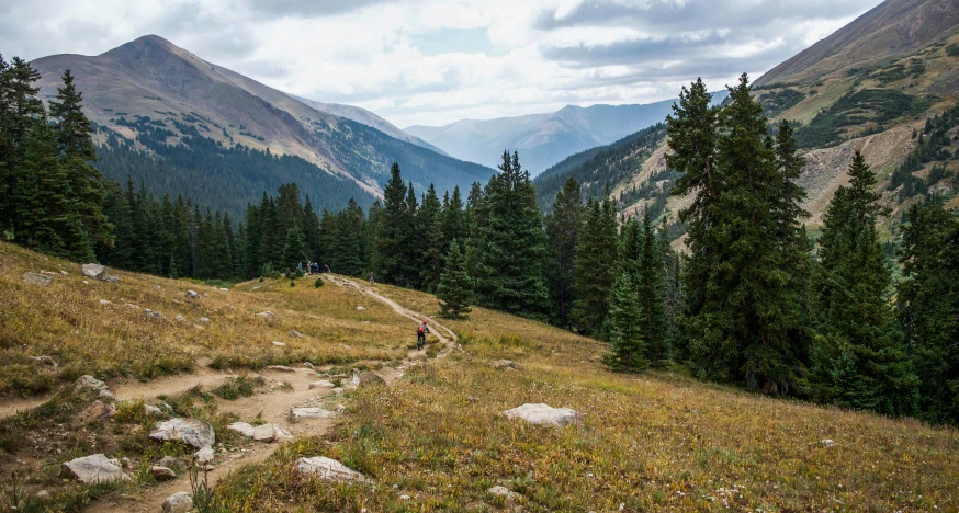 an unpaved trail up the side of a hill with a view of mountains