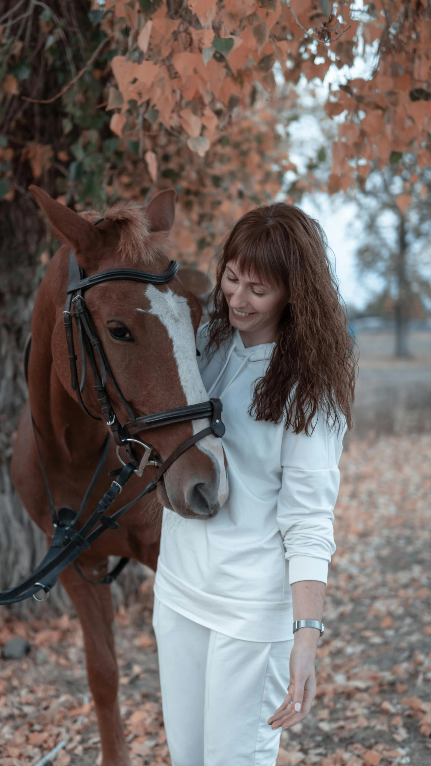 a woman is standing next to a horse under trees