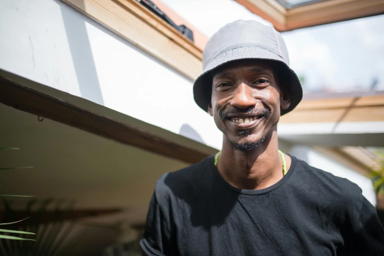 a man wearing a grey hat and t - shirt looks at the camera