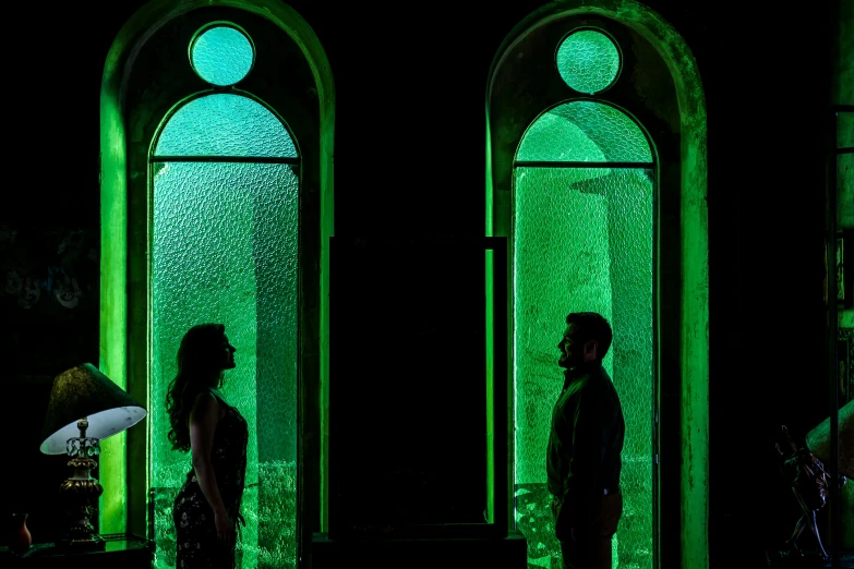 two men standing side by side in front of a green wall