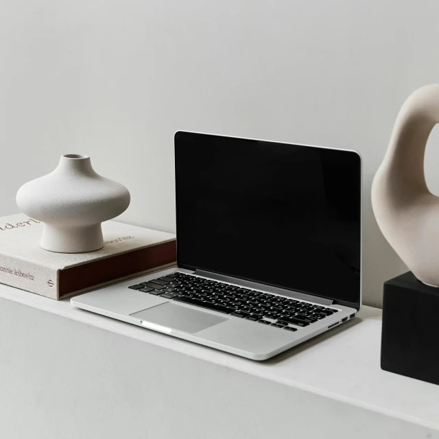 a laptop sits on a ledge next to vases