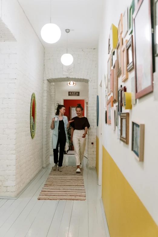 a woman standing in front of a room with pictures on the wall