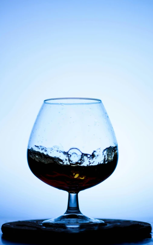 glass with liquid sitting on a coaster against a blue background