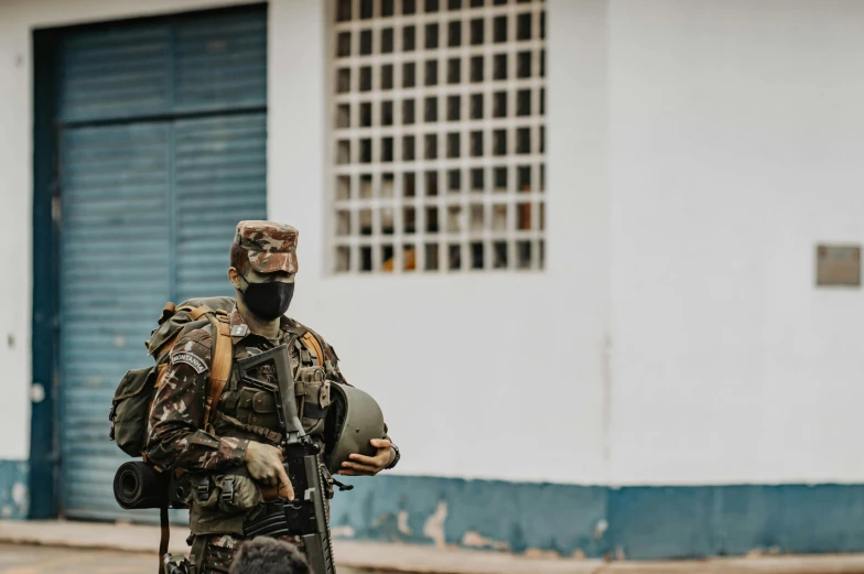 the soldier is wearing camouflage clothes and is carrying an umbrella