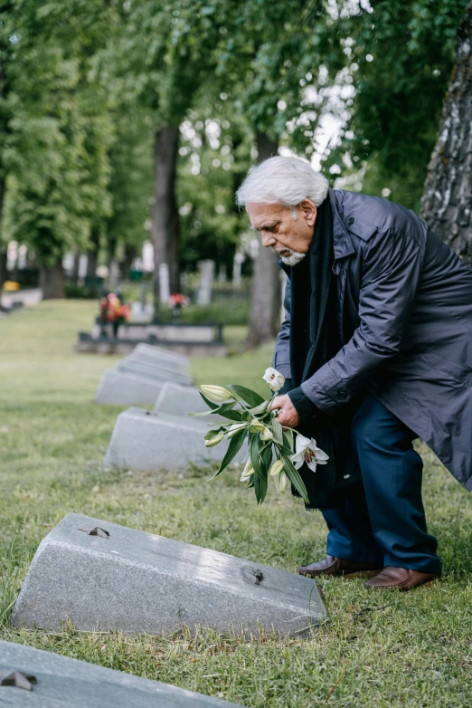 a man is smelling a bouquet of flowers at the headstones