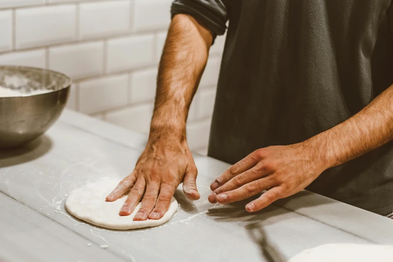 a man making food with a floured ball on a table