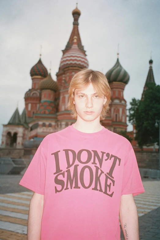 a young man standing in front of an old church with the text i don't smoke on it