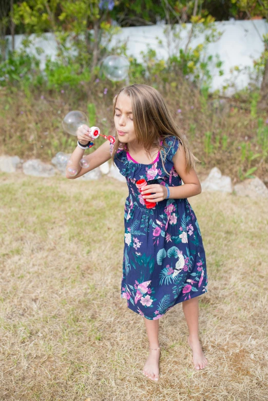 little girl blowing bubble with water in her hand