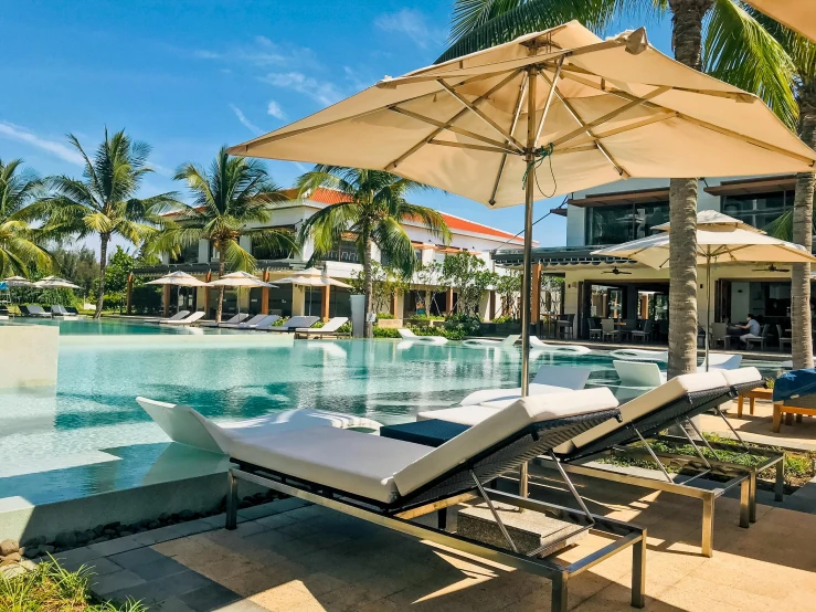 an umbrella stands near the pool as loungers lay on the floor