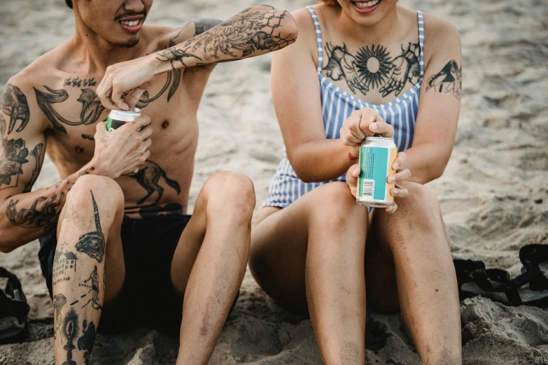 a man and woman sitting in the sand on the beach