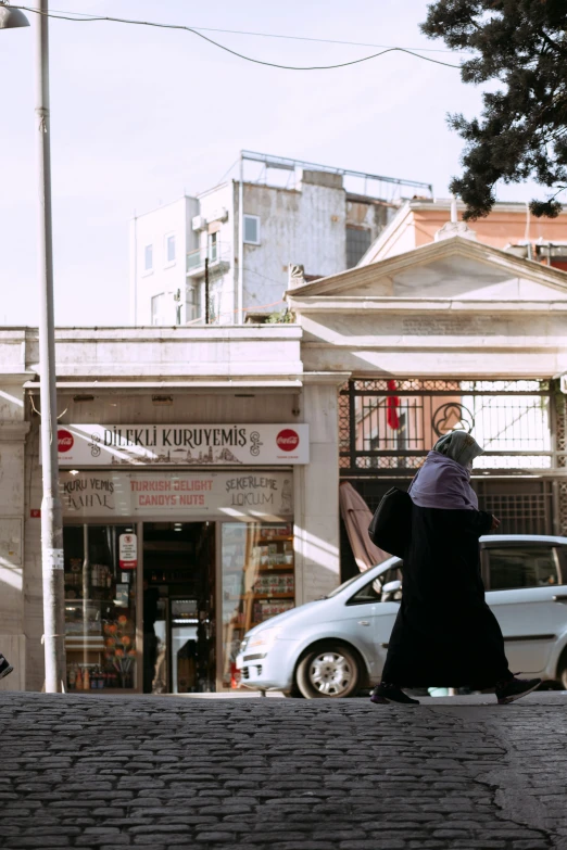 woman in black coat walking on sidewalk near storefront