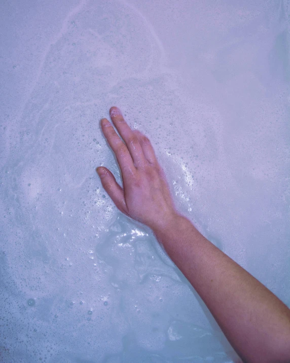 a hand is resting on the surface of a bathtub