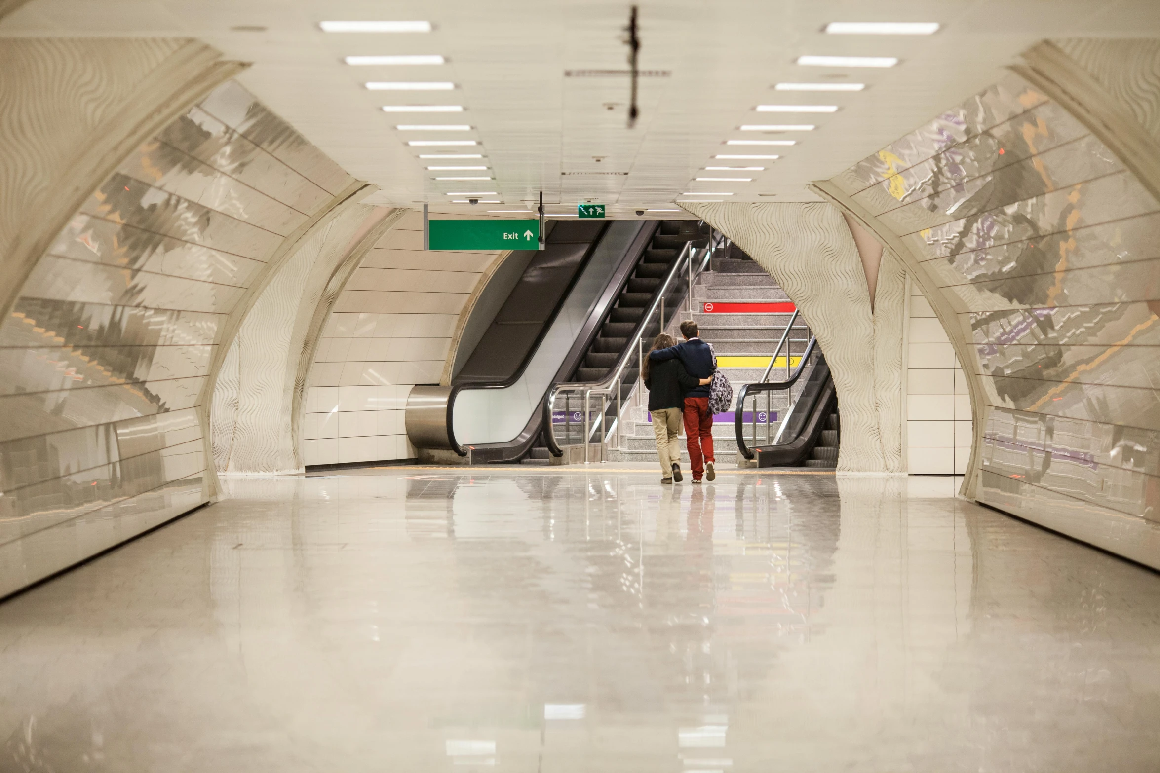 the subway platform has an escalator and stairs leading up to the platforms