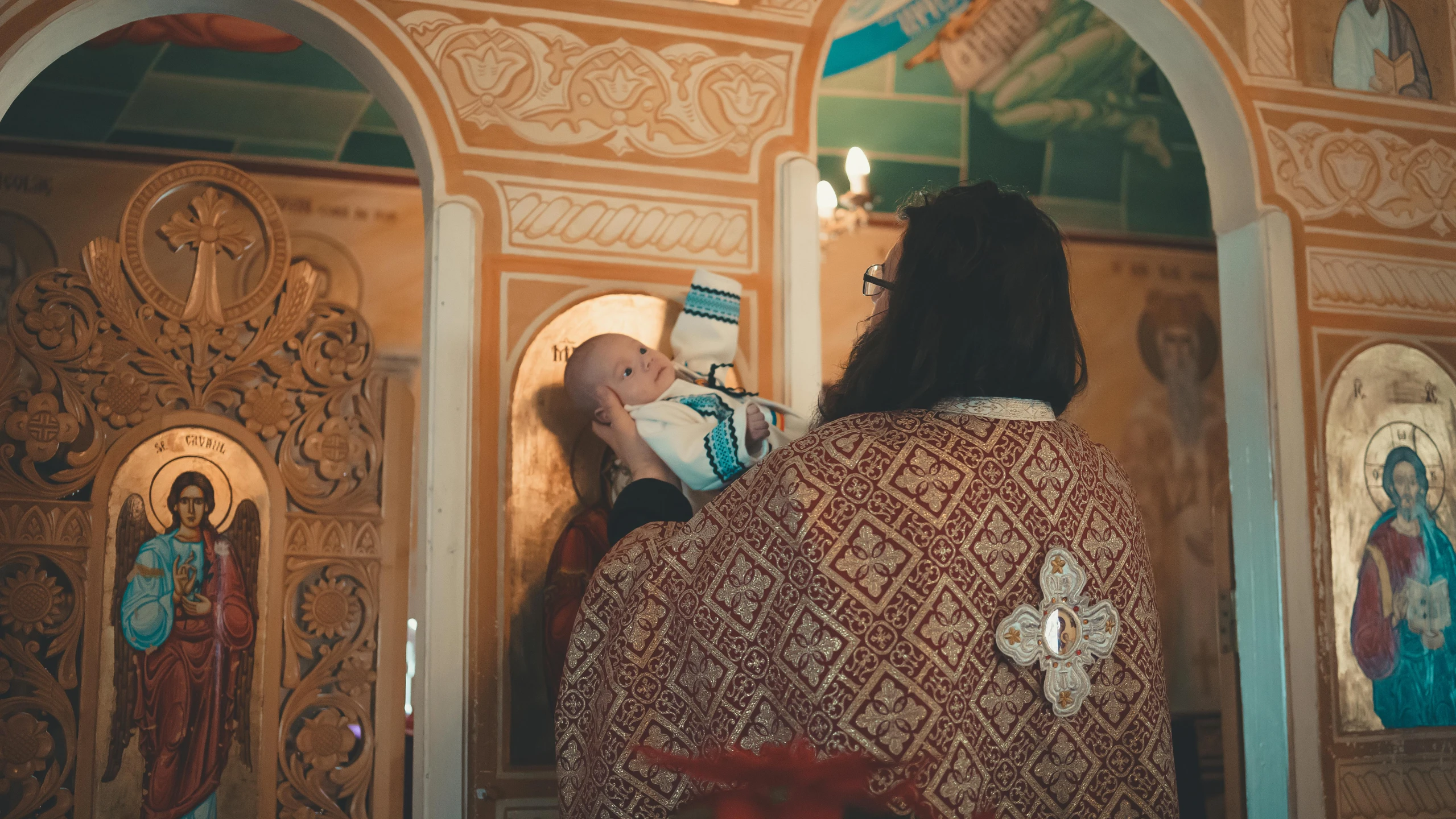 a person holding a baby in front of some paintings