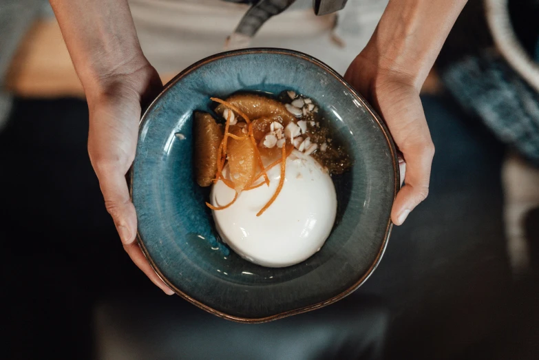 a hand holding a bowl of food with an orange