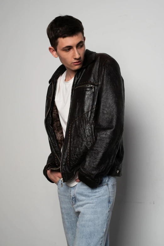 a man standing wearing a black leather jacket and jeans