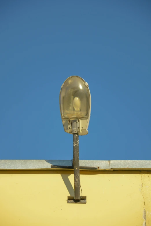 a yellow wall with a clear blue sky and a street light