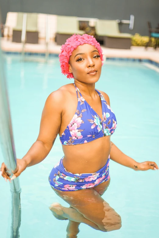 a young woman in a floral bikinisuit poses by the edge of the pool