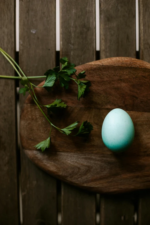 a green vase filled with flowers next to an egg