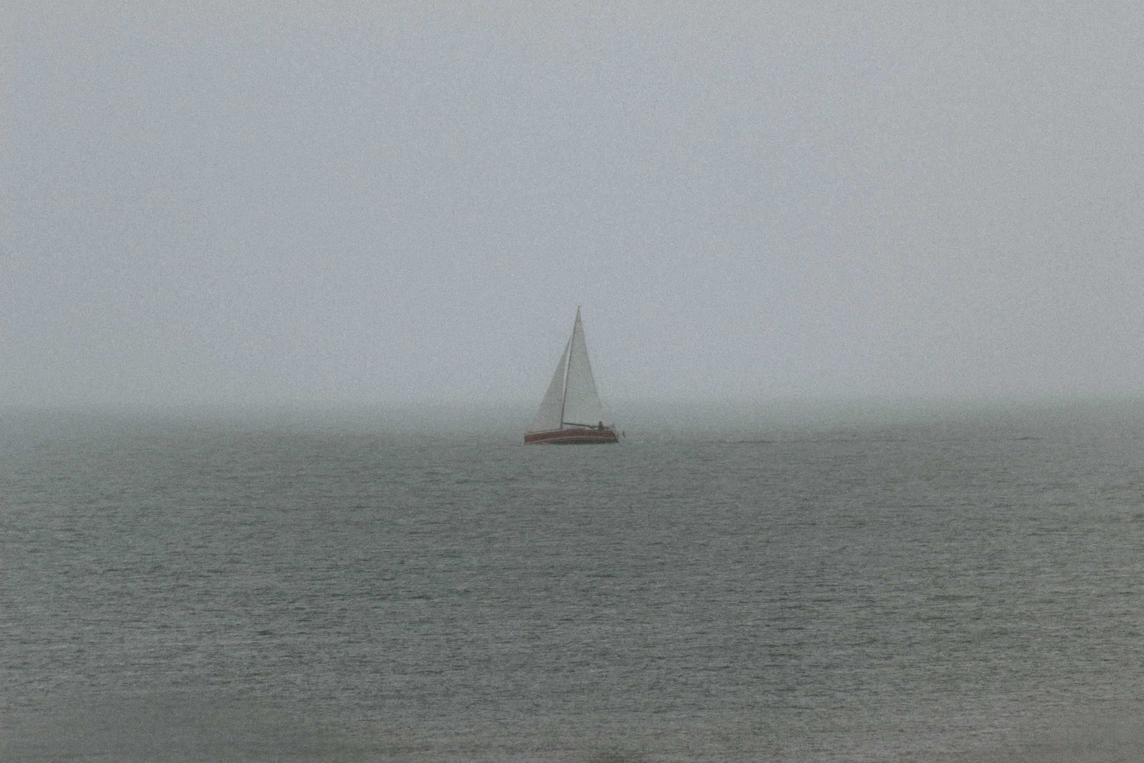 the sailboat floats in the mist on an overcast day