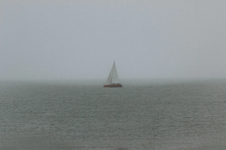 the sailboat floats in the mist on an overcast day