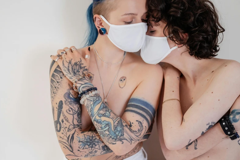 two people that have tattoos and face masks