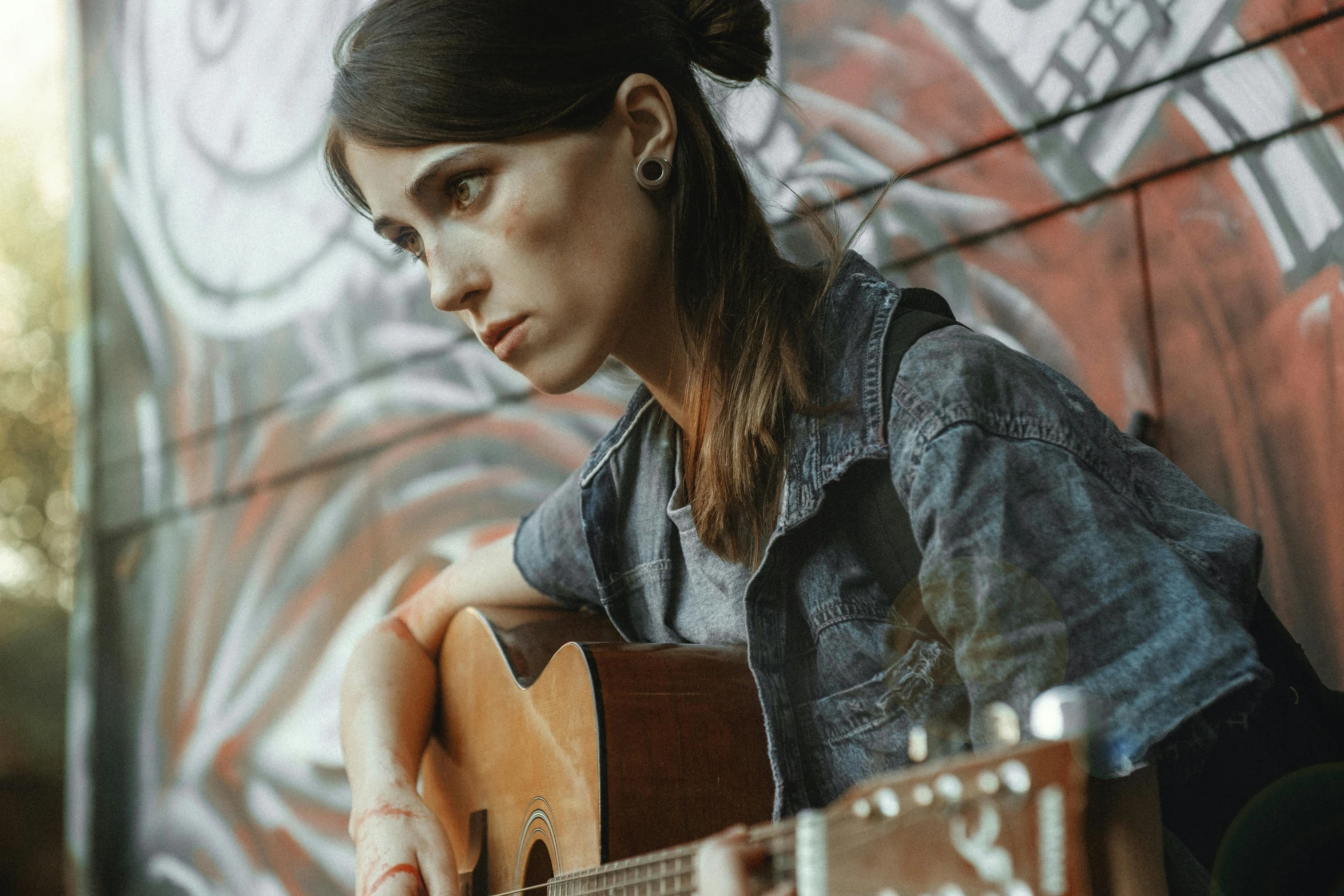 woman holding guitar playing near large painting