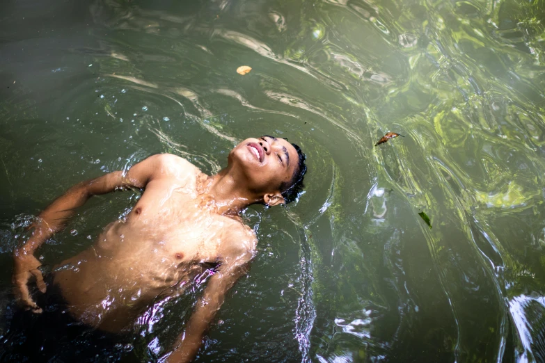 young man swimming in shallow water near shoreline