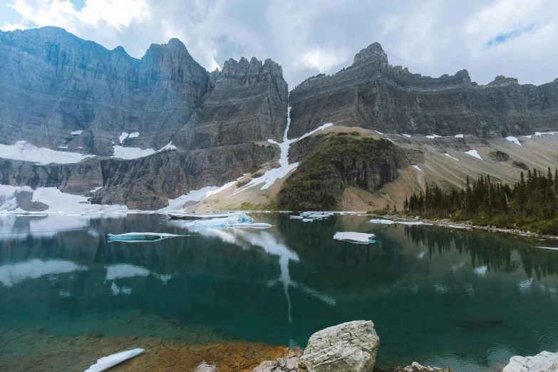 mountains reflected in the calm water near the forest