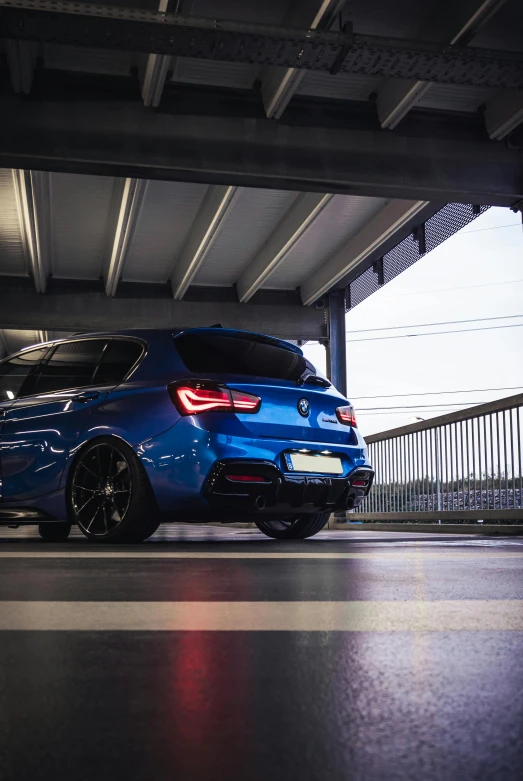 a blue bmw vehicle is parked underneath an overpass