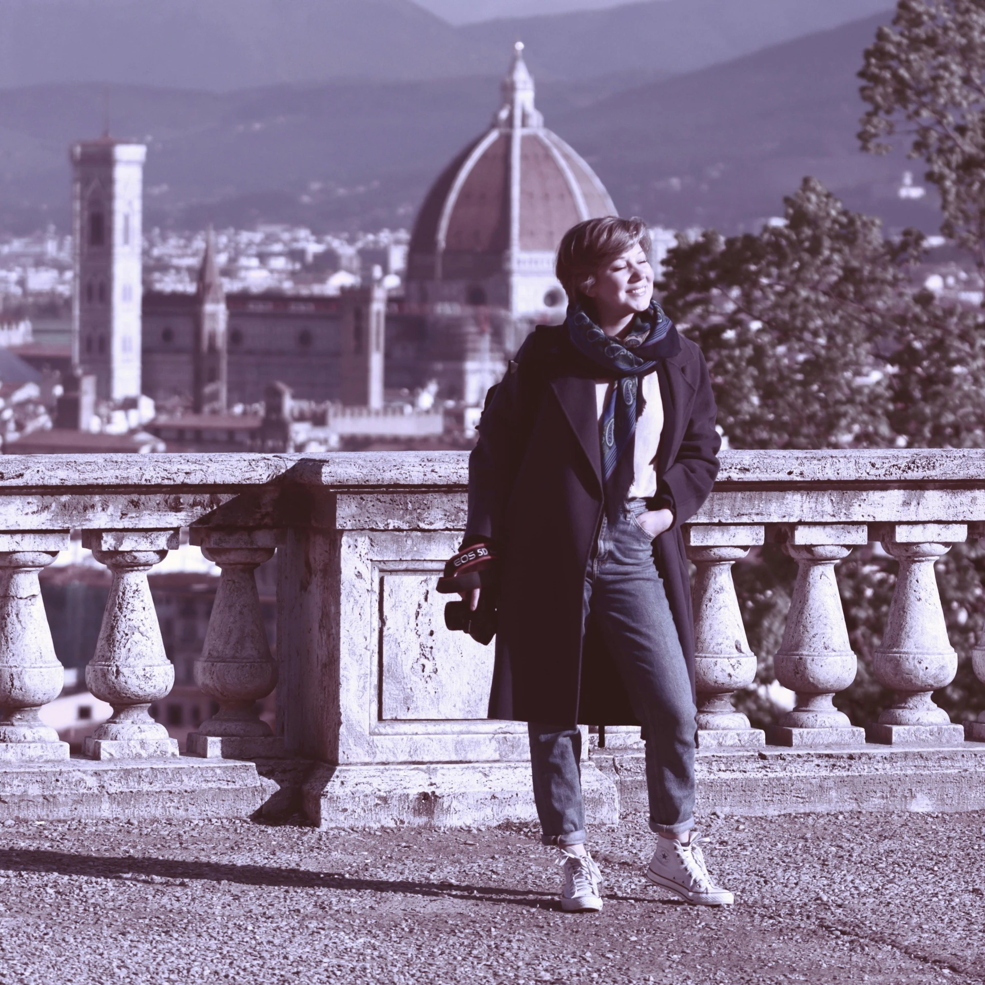 a woman poses in front of an ornate bridge